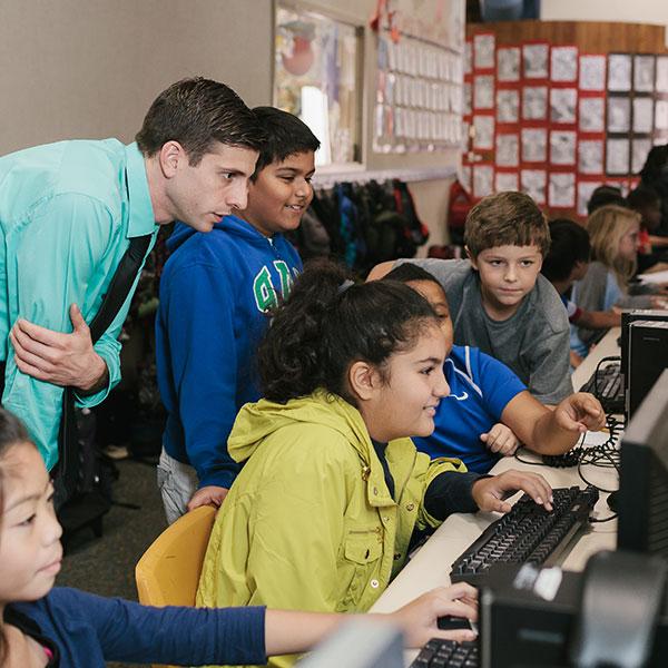 Teacher working with students on a computer